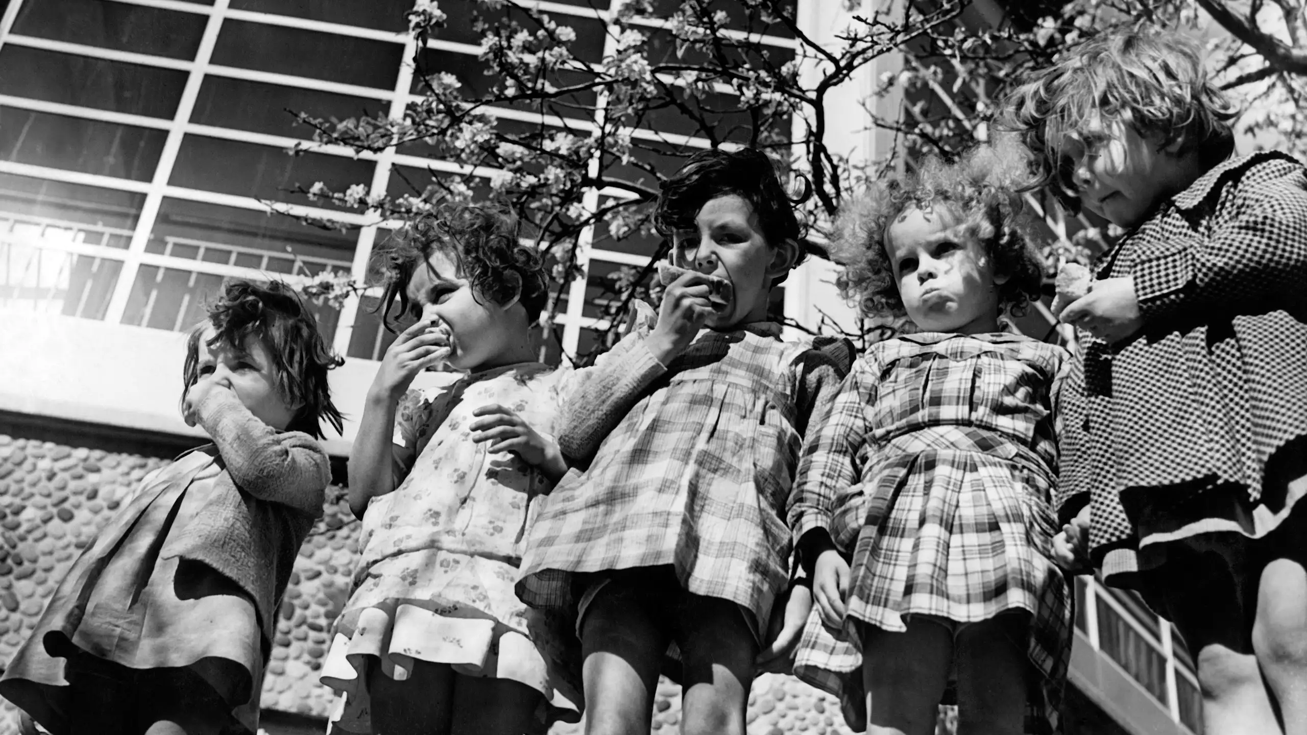Des élèves prennent leur goûter dans la cour de l'école pilote de Suresnes, dans les années 1930.