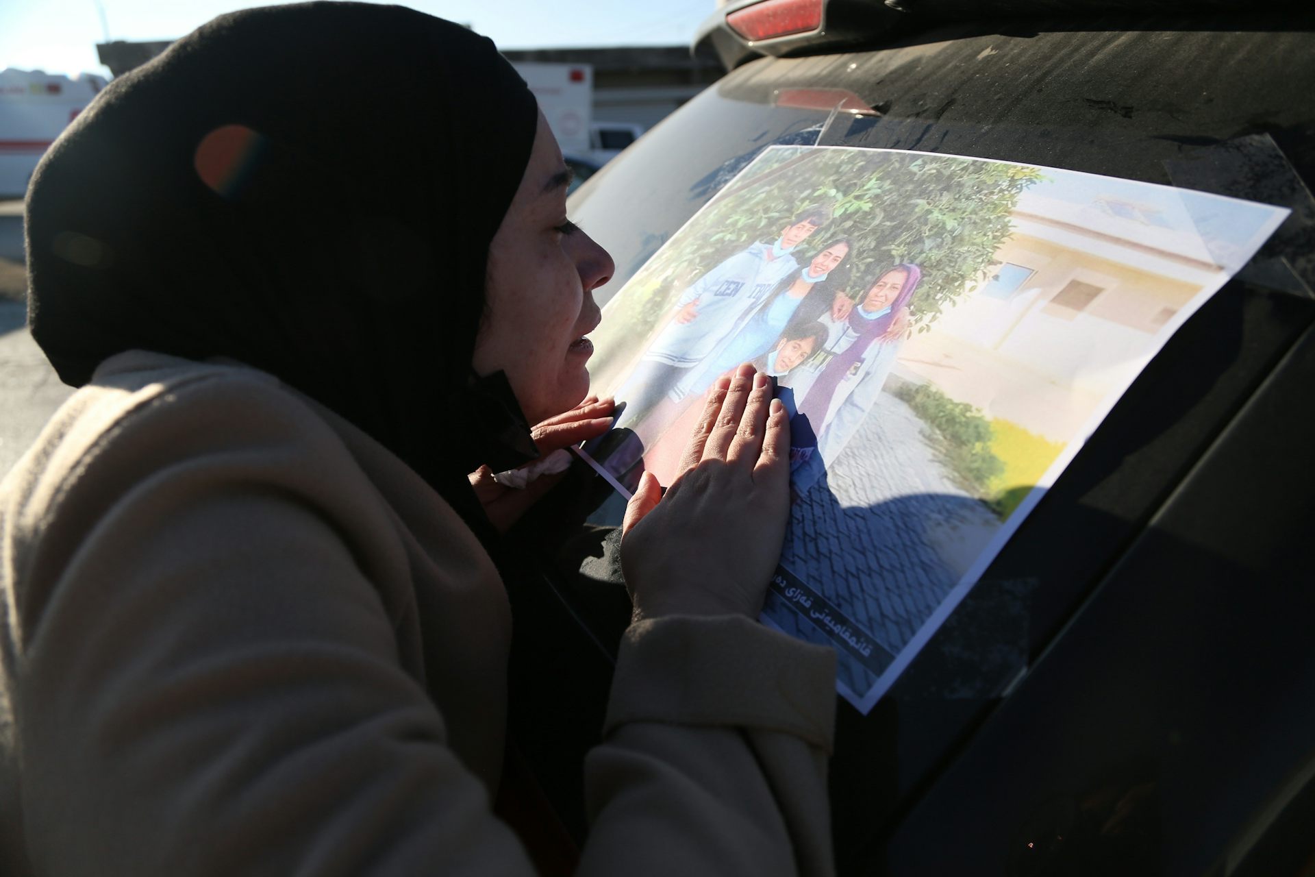 Une femme en deuil touche une photo d'une mère et de ses trois enfants.