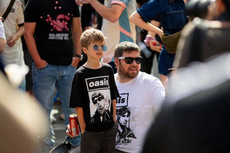 father with his young son in oasis t-shirts at the band's 2025 reunion tour in the uk