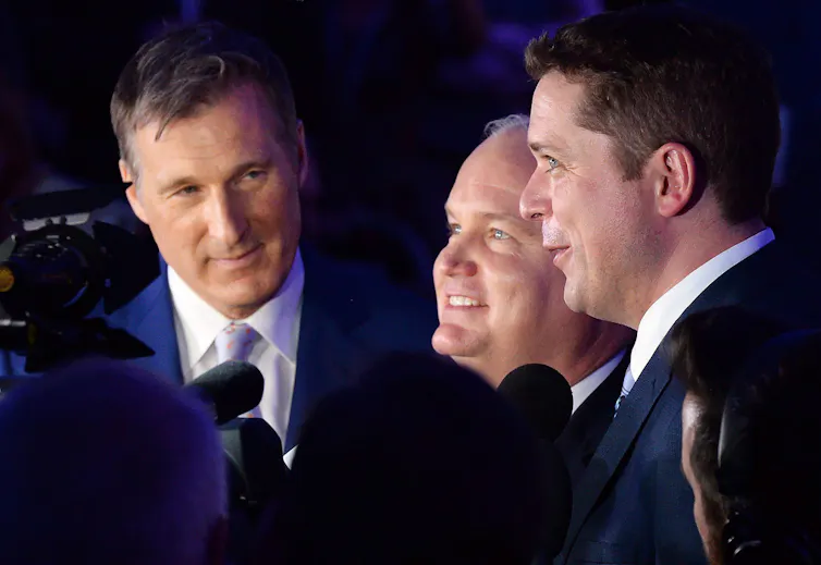 Three middle-aged white men stand in a row smiling.