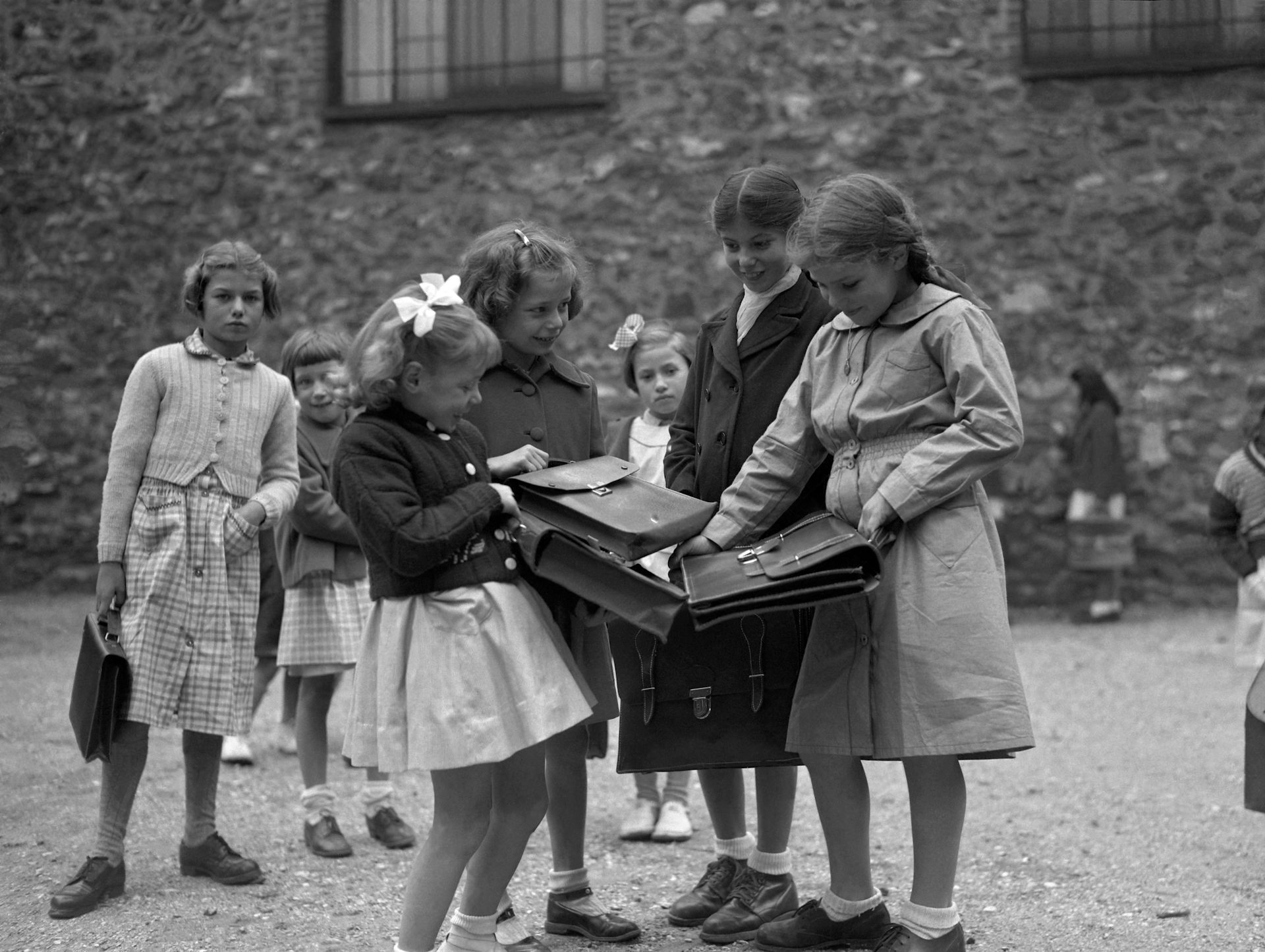 Des écolières françaises se montrent mutuellement leurs tout nouveaux cartables dans une école primaire de la région parisienne, en1951.