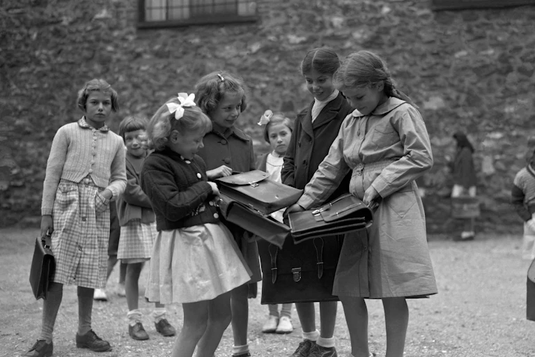 Des écolières françaises se montrent mutuellement leurs tout nouveaux cartables dans une école primaire de la région parisienne, en1951.
