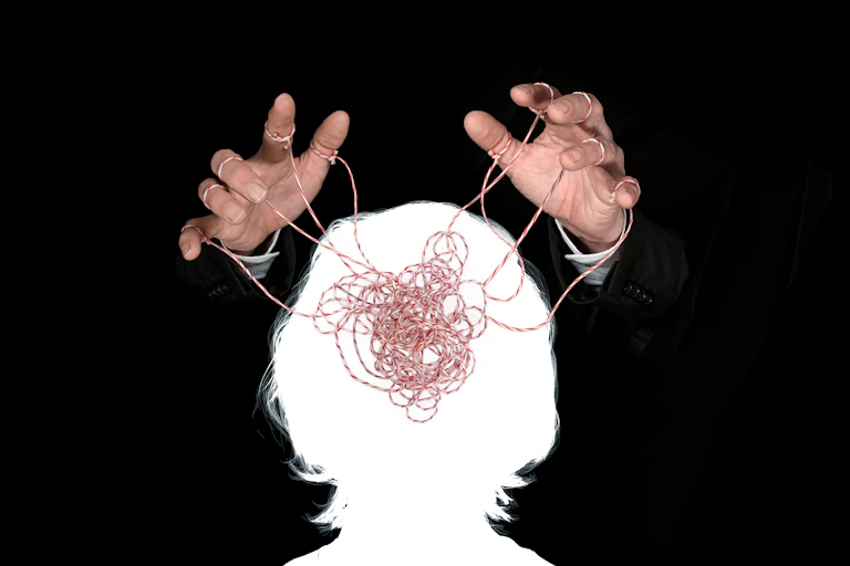 Hands about the outline of a head filled with tangled string;