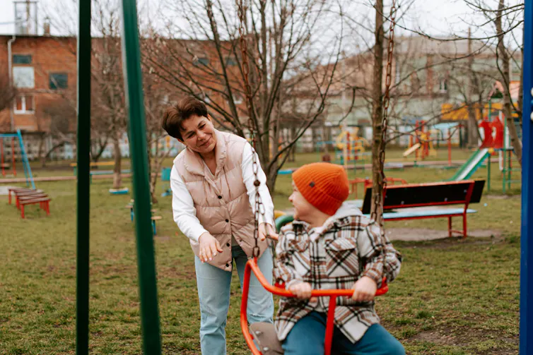 an older dark-haired woman plays with a boy at a playground