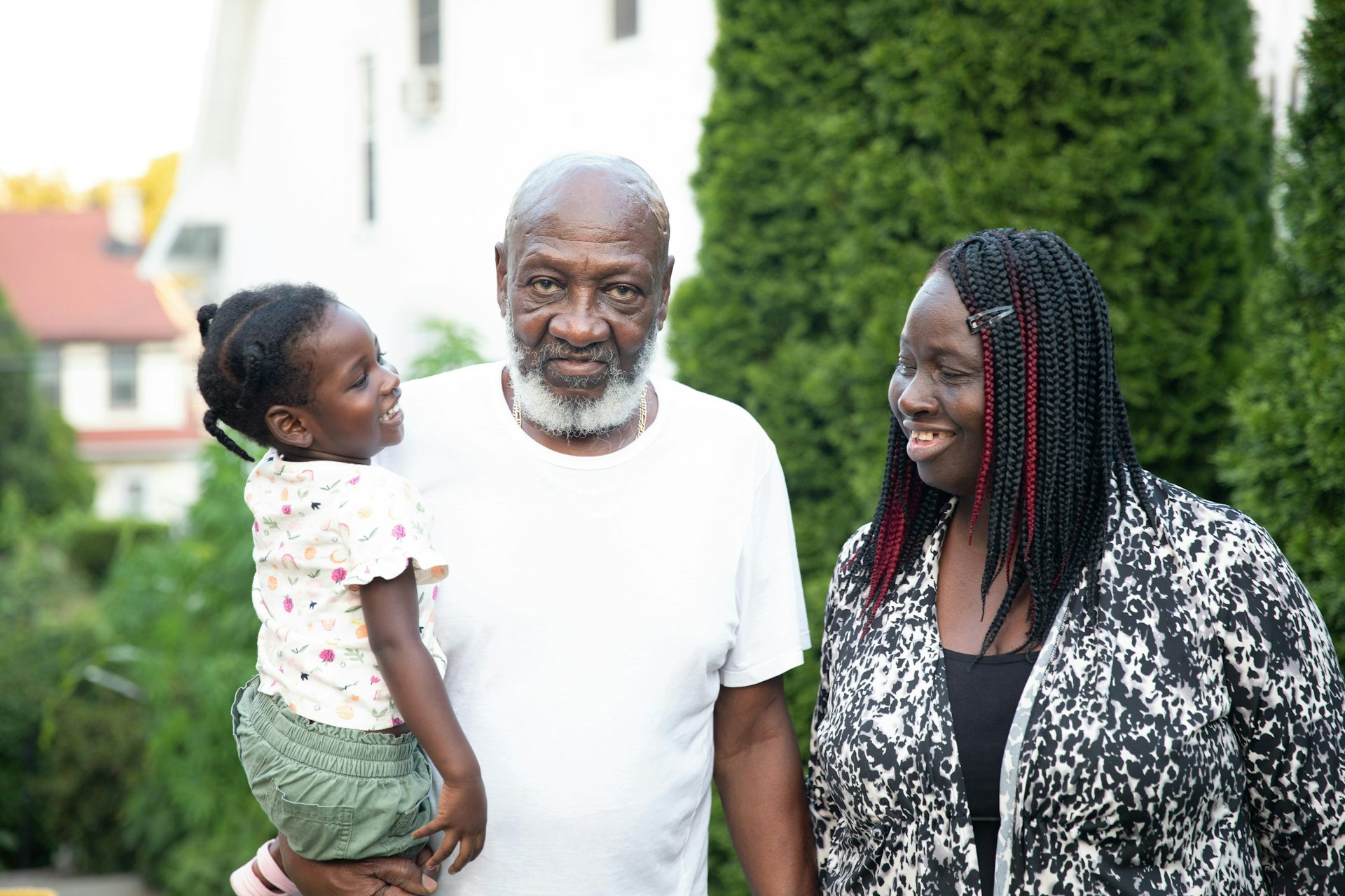 El hombre negro mantiene a una niña sonriente mientras está de pie junto a la mujer negra más joven.