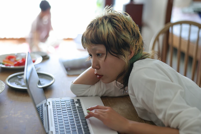 Woman reads on her laptop at the kitchen table