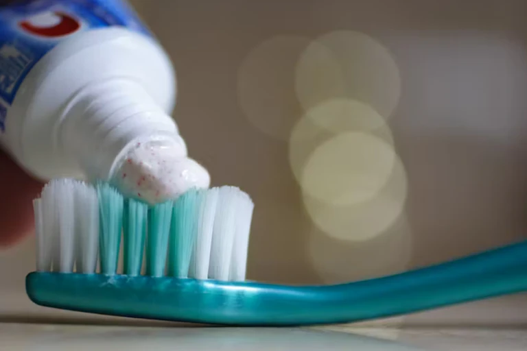 A toothbrush upon which toothpaste containing microbeads is being squeezed
