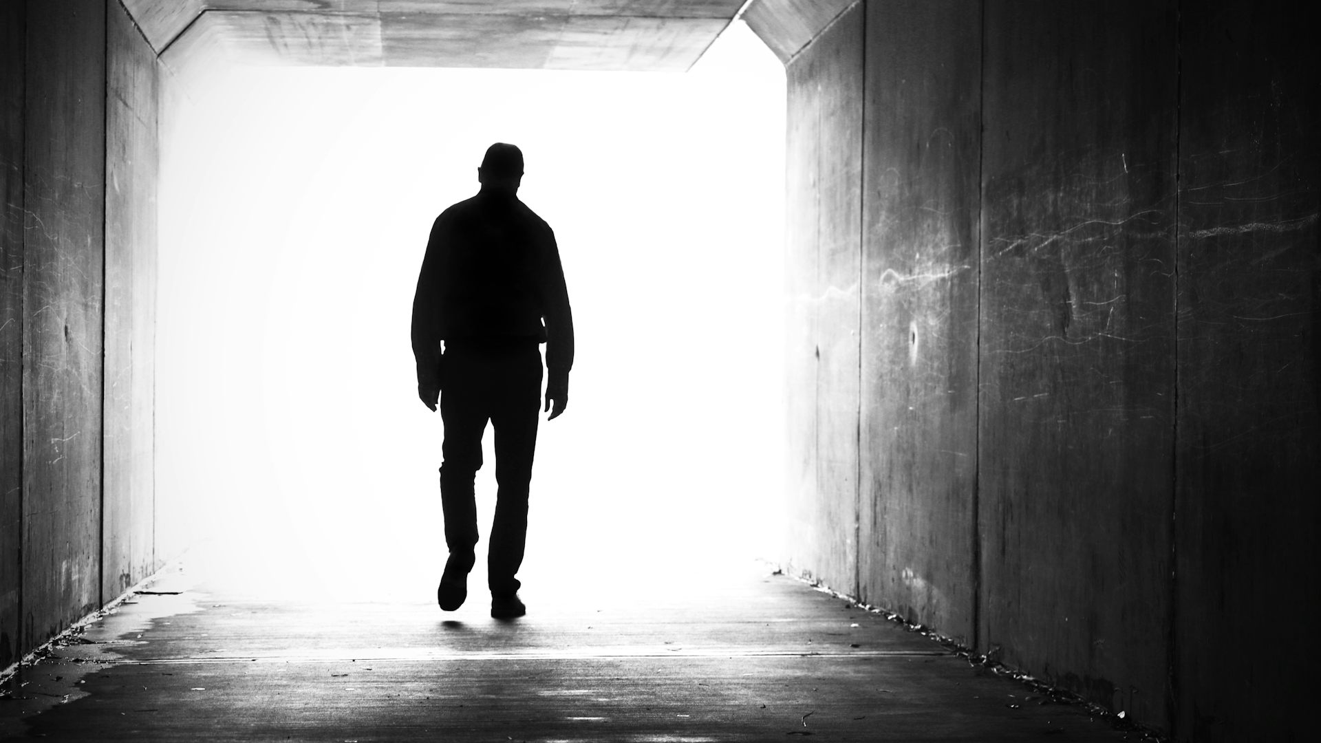 Silhouette of man walking through underpass tunnel.
