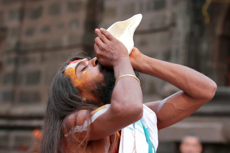 Man blowing into a conch shell.