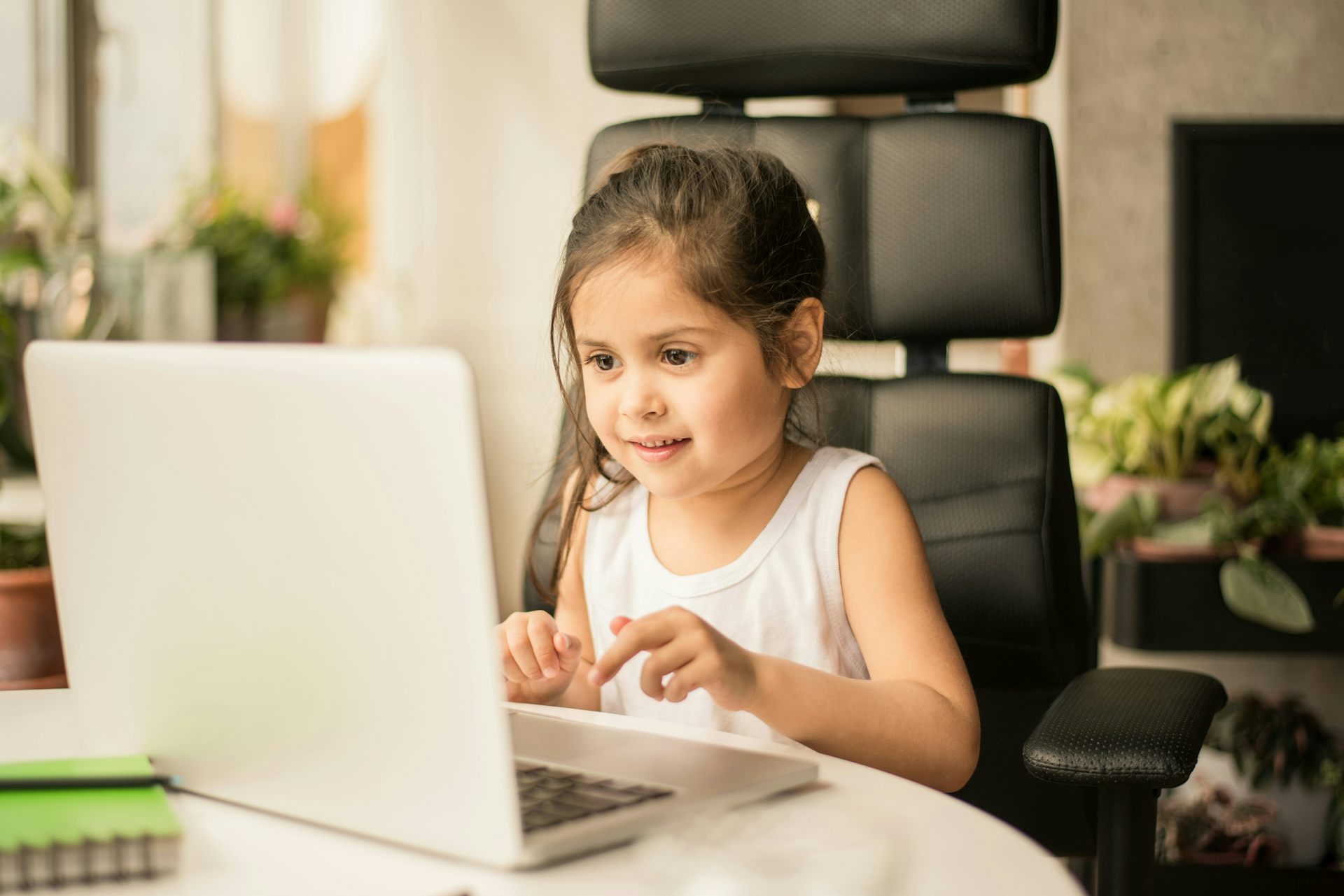 a young girl sits at a laptop