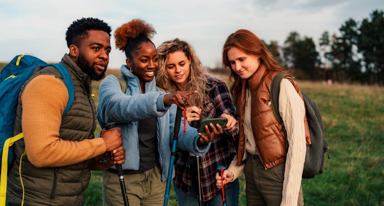 Group of young people hiking and looking at phone