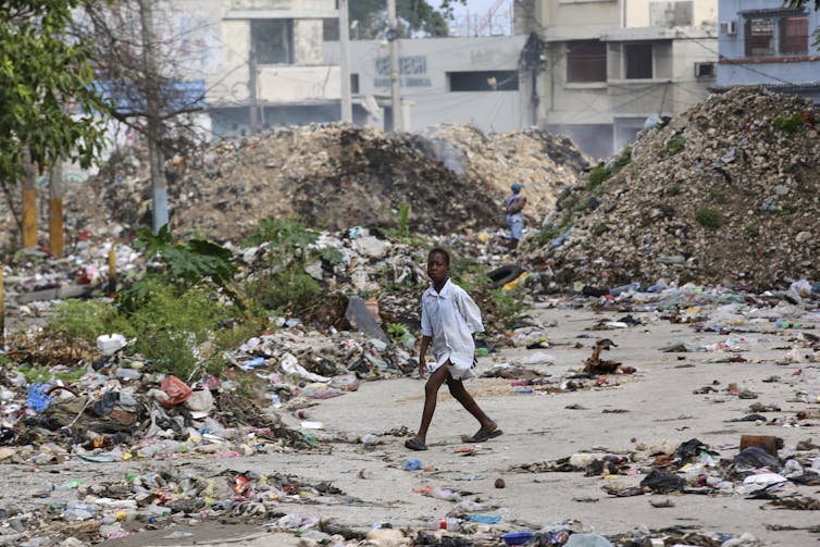 El joven cruza la basura de la calle en la basura.