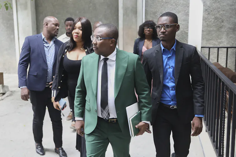 A man in an emerald green suit walks into a courthouse.