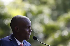 A Black man in profile with a microphone in front of his mouth.