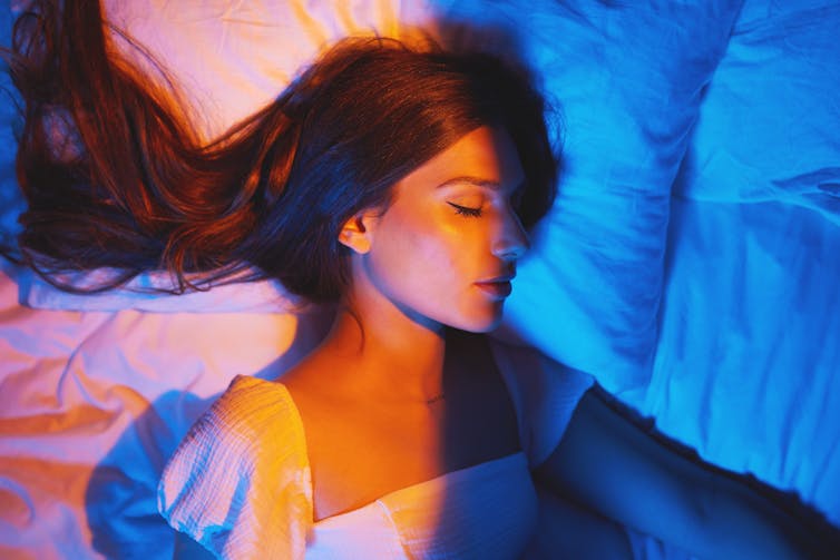 Woman asleep half in yellow light half in blue