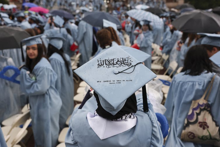 A student wears a graduation cap with a verse from Koran written on it.