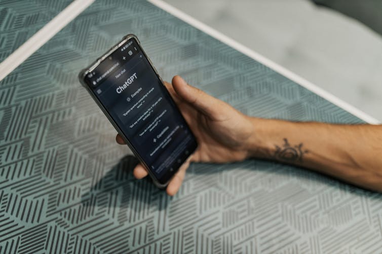 a hand holding a smartphone showing ChatGPT on the screen