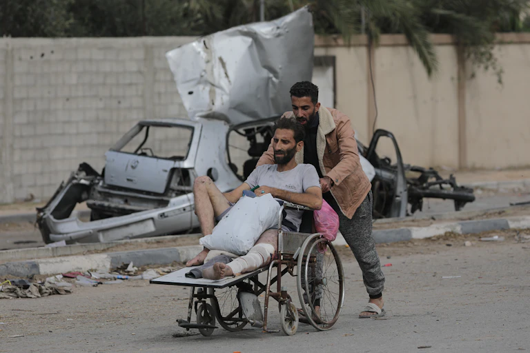 A man pushes an injured Palestinian on a wheelchair in November 2023.