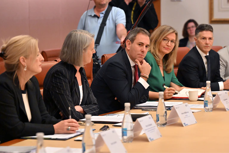 Men and women in suits sit at a meeting table