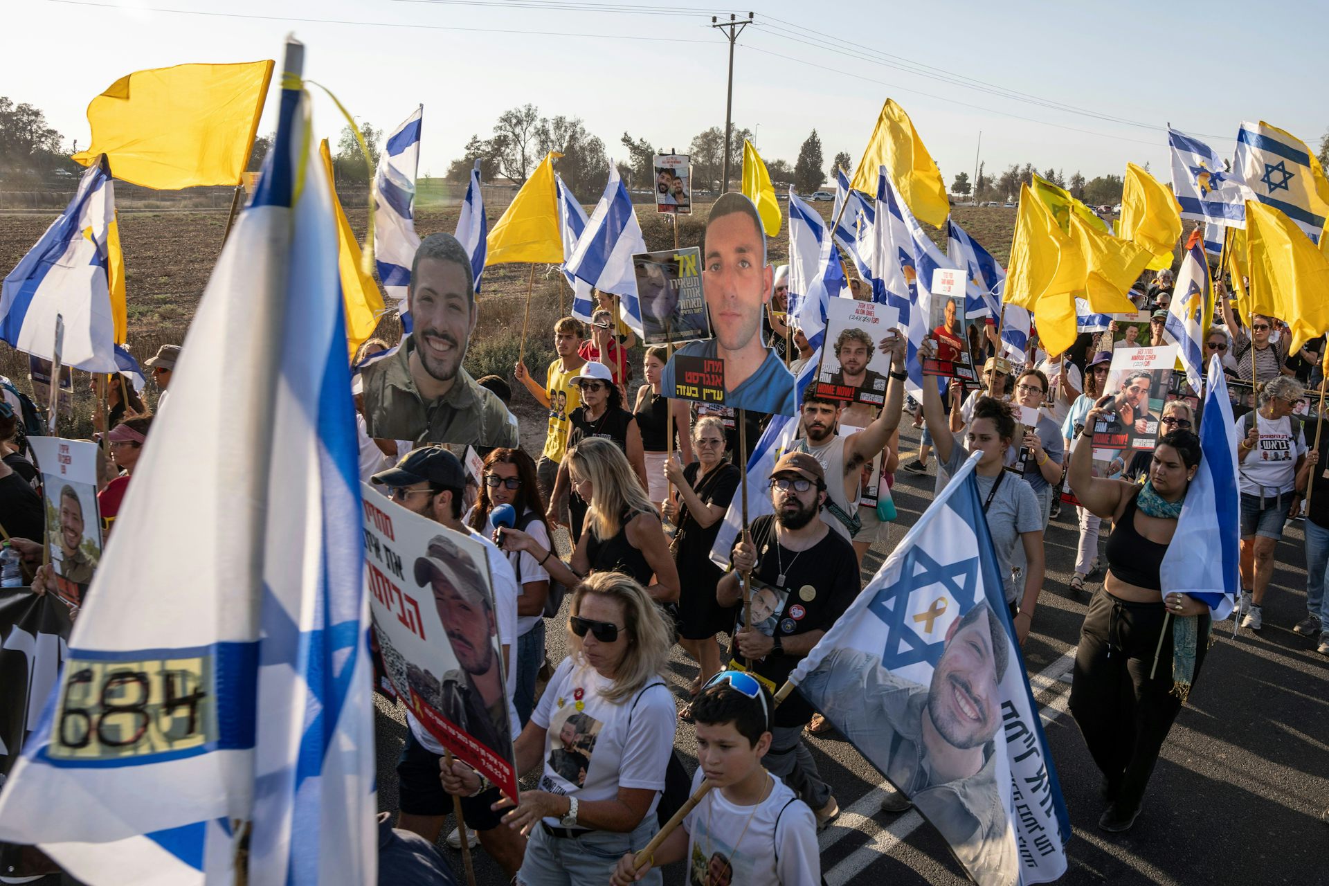 Large demonstration of Israeli citizens carrying flags and banners with photographs of hostages.