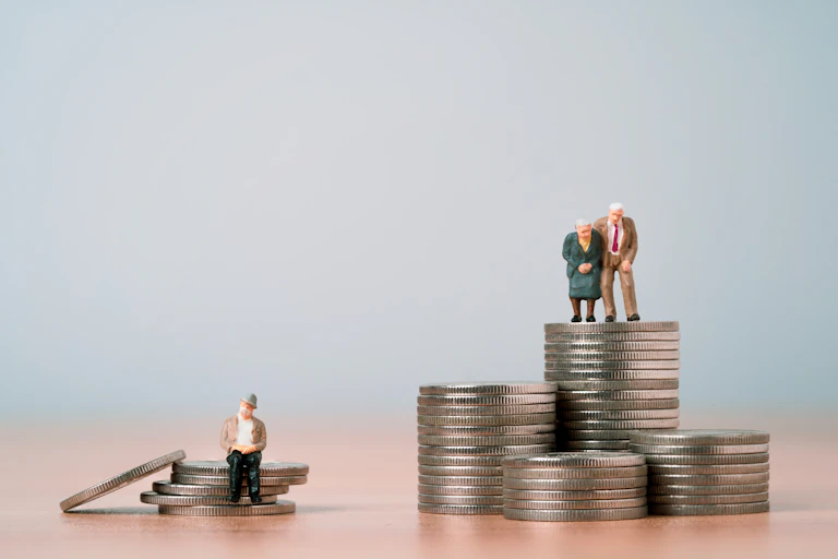deux figurines représentant des personnes âgées sur un tas de pièce de monnaie