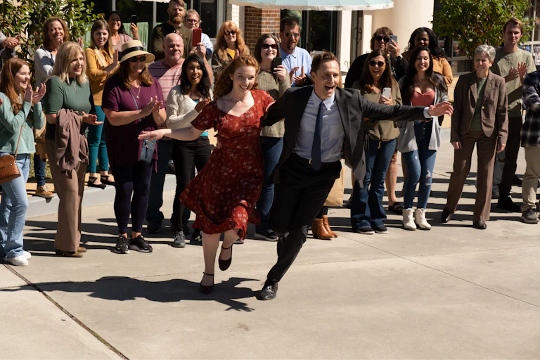 Tom Hiddleston and Annalise Basso dancing in a busy street