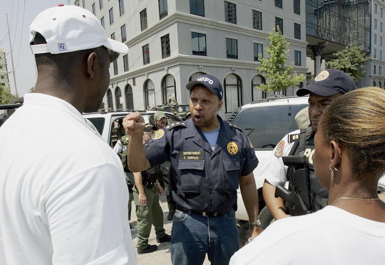 A police officer points at someone while talking to people on a downtown street.
