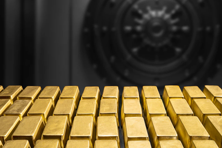 gold bullion bars in front of a vault.