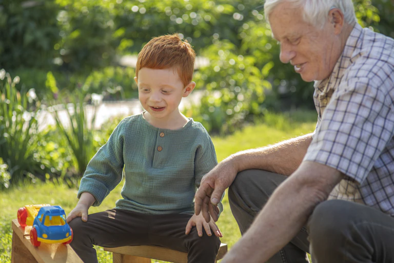A boy playing with a senior man outside.