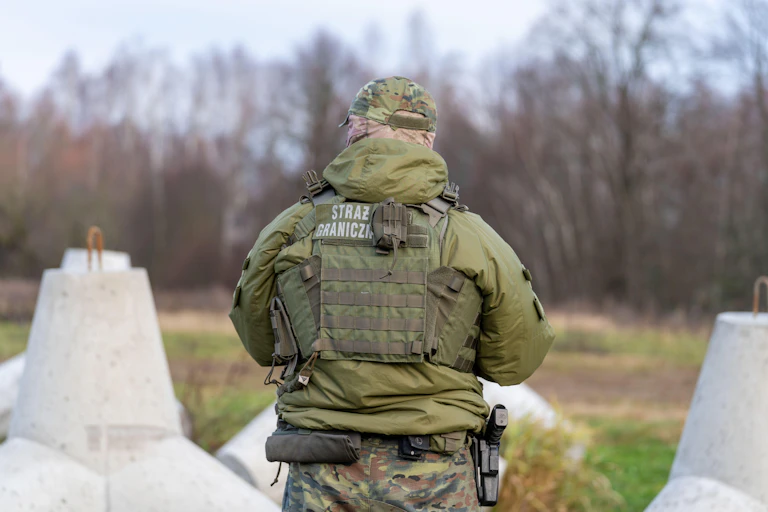 A Polish border guard with his back to the camera.