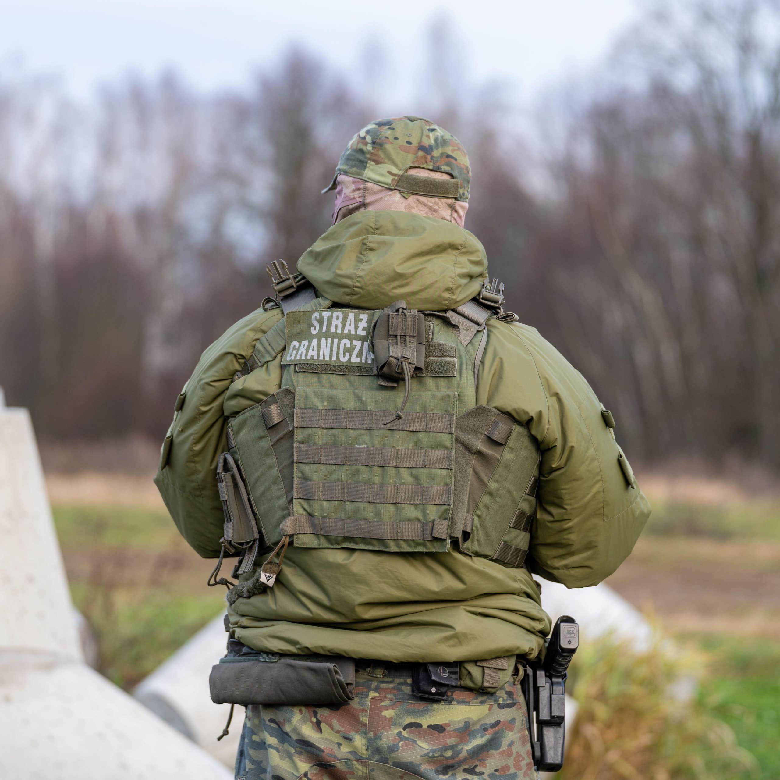 A Polish border guard with his back to the camera.