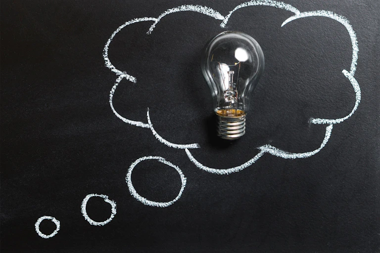 Graphic of 'thought bubble' drawn on a blackboard in chalk, with a lightbulb inside it