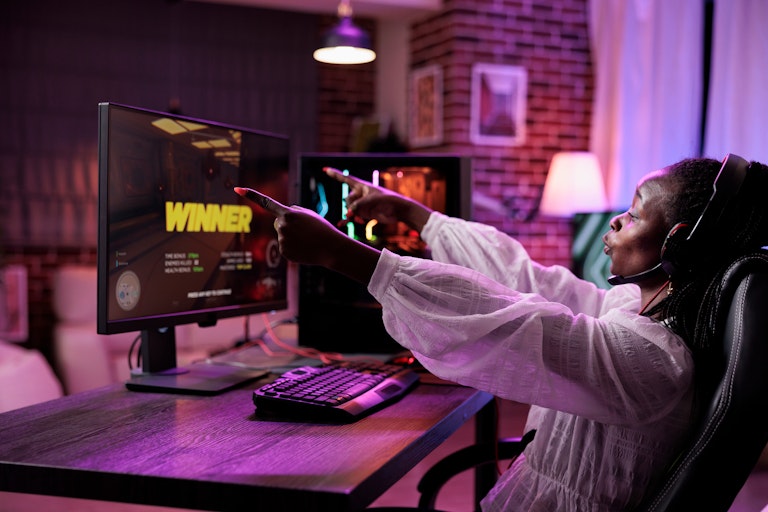 Woman playing a video game on her computer. The screen says 'winner'.