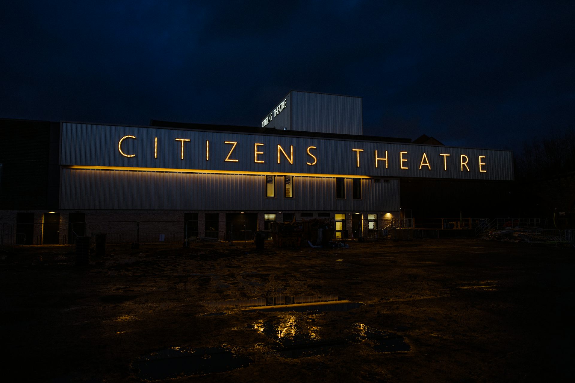 A night time shot of the Citizens Theatre with yellow neon signage.