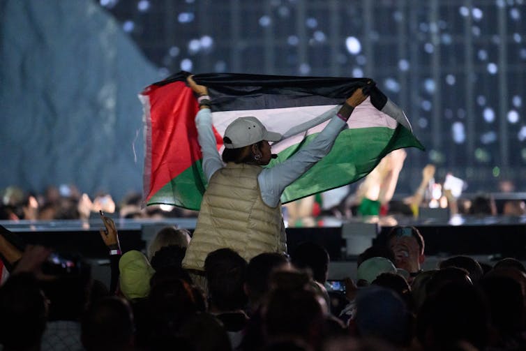 A person holds aloft a red, black, white and green flag