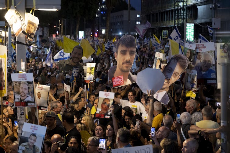 People hold aloft placards and imges of men's faces/