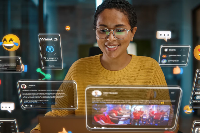 A smiling woman looks at numerous screens and emojis