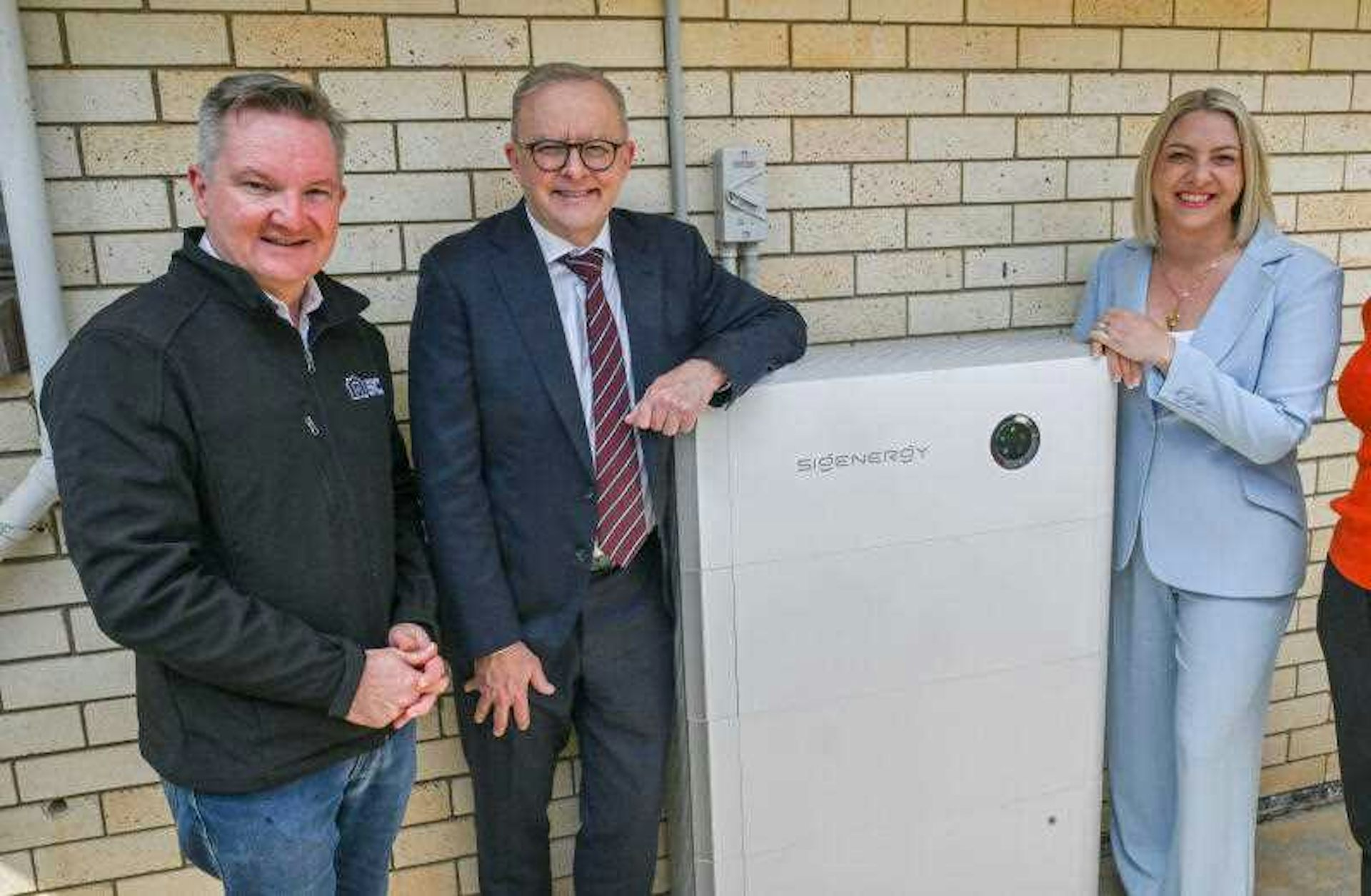 women and a woman stand next to a home solar battery.