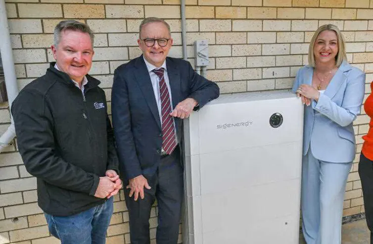 women and a woman stand next to a home solar battery.