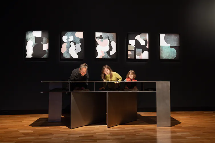 A mother and two children experience the artwork.