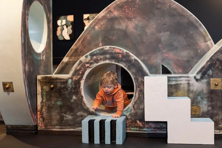 A toddler crawls through the art work.