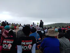 A group of people protesting on rural land wearing tshirts that say