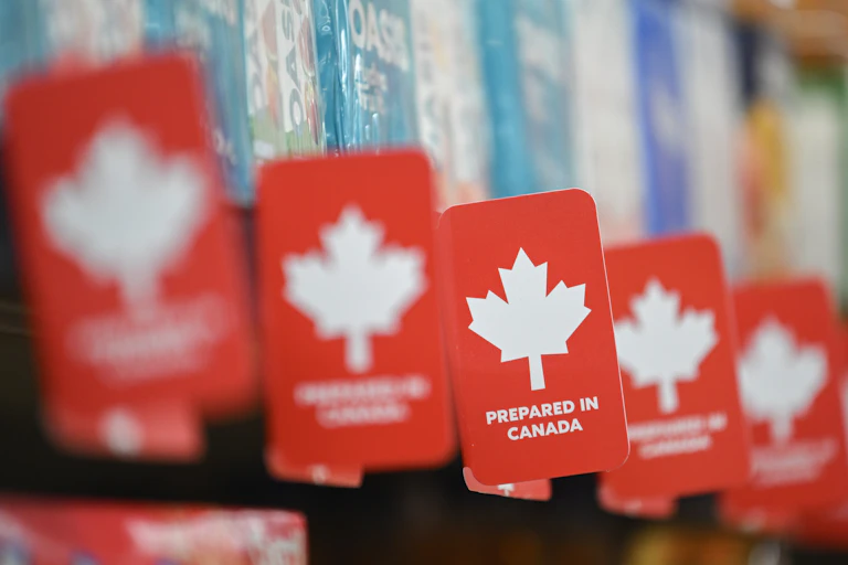 A row of red and white 'prepared in canada' labels along a grocery store shelf