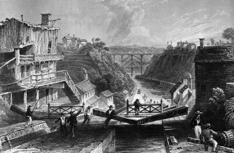 Men work on a wooden structure over a narrow canal.