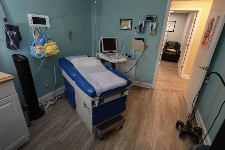 An examination room in an abortion clinic shows an exam table and ultrasound machine.