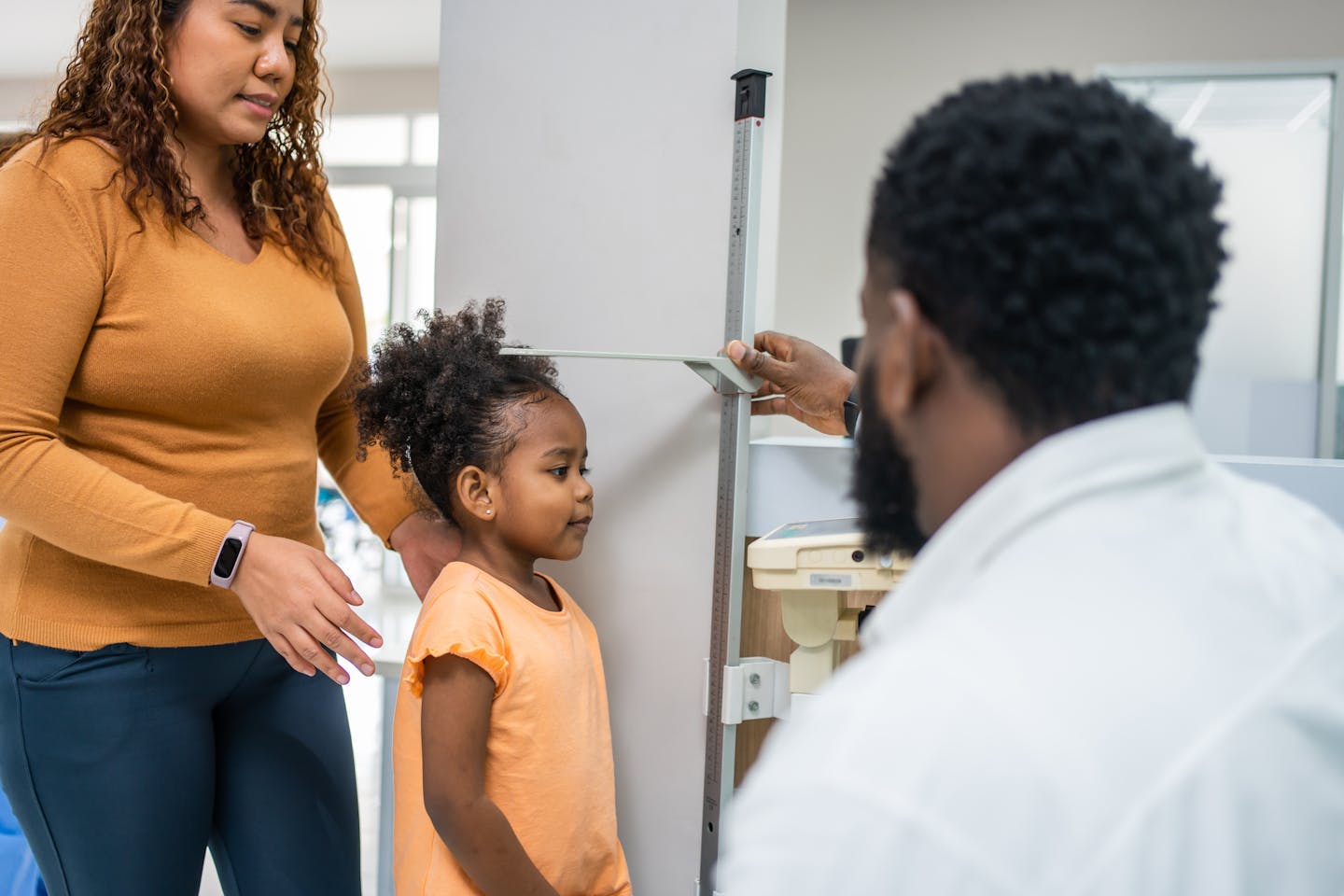 Doctor measures a young child's height at a medical checkup.
