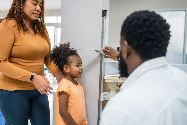 Doctor measures a young child's height at a medical checkup.