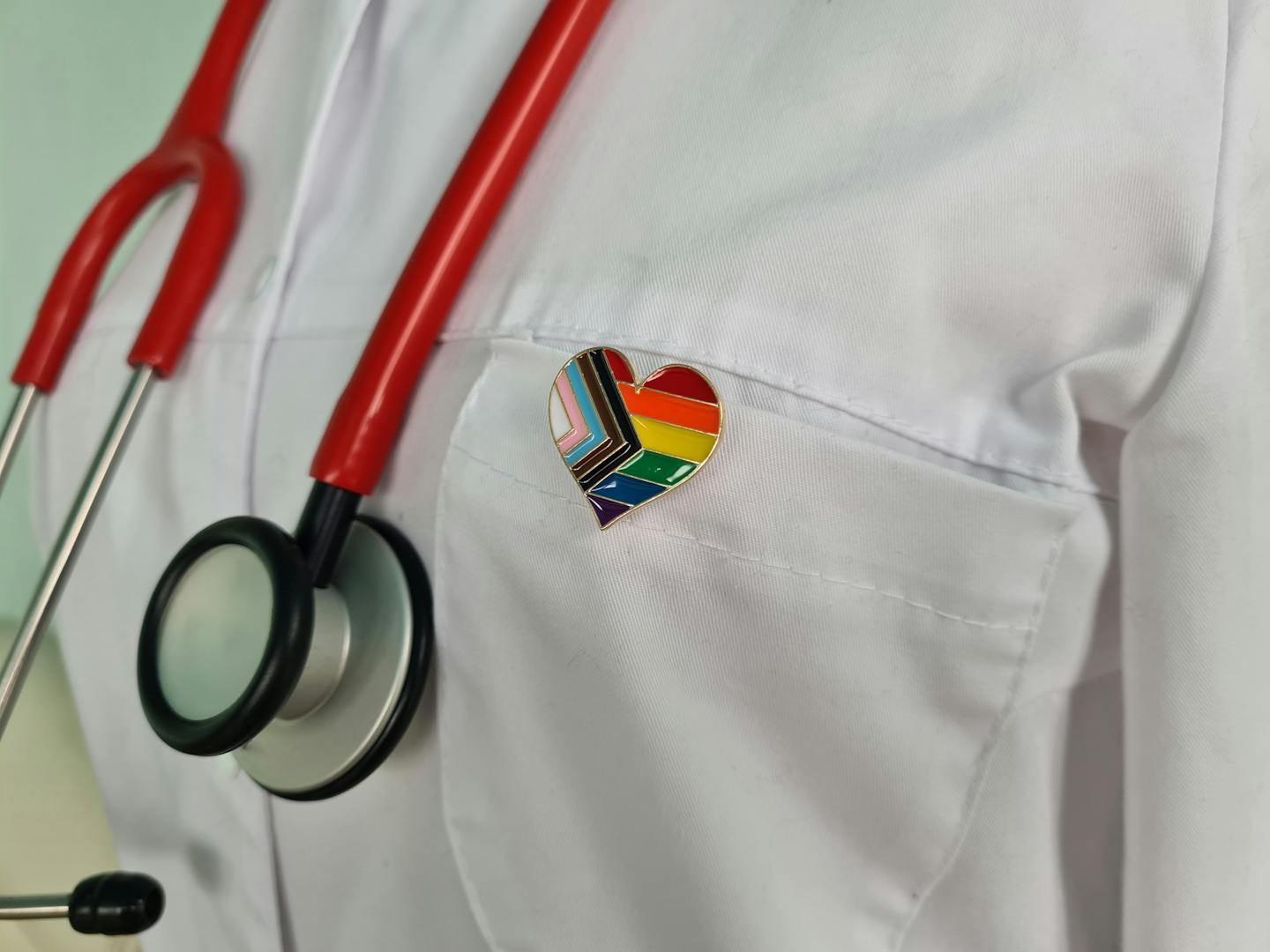 Silhouette of doctor in white coat with stethoscope and LGBTQ+ pin on pocket