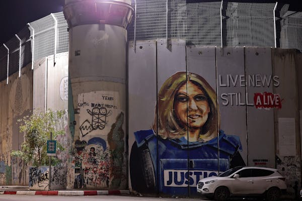 The image of a woman with a flak jacket with 'justice' written on it is seen on a wall