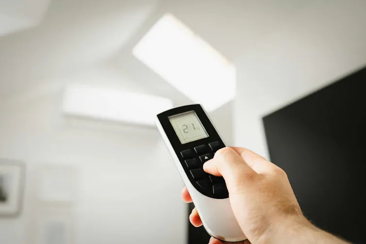 Man's hand holding remote for an air conditioner